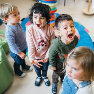 young children in a classroom listening to an early years student