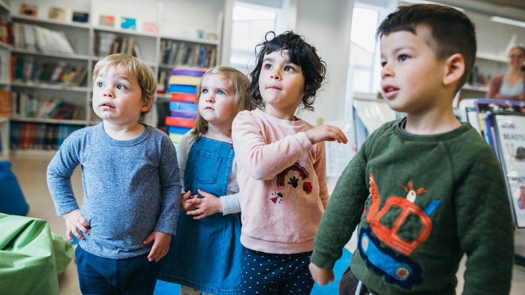 A group of four early years children stood in the classroom resources library