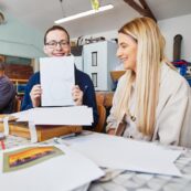 Smiling people, one holding a pencil drawing