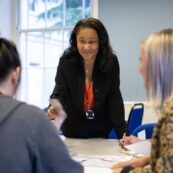 A tutor leaning over to help two students