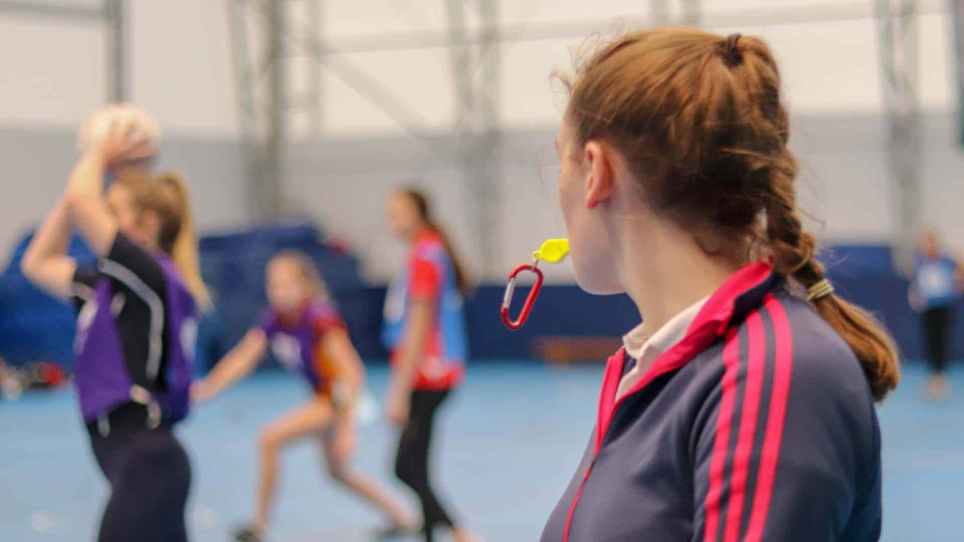 Physical Education student leading a netball session, blowing on a whistle