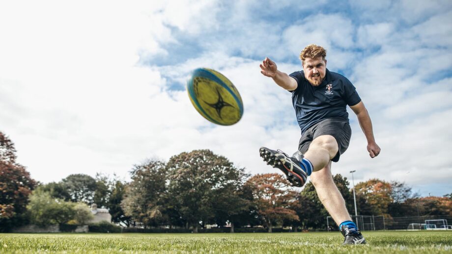 Student kicking rugby ball