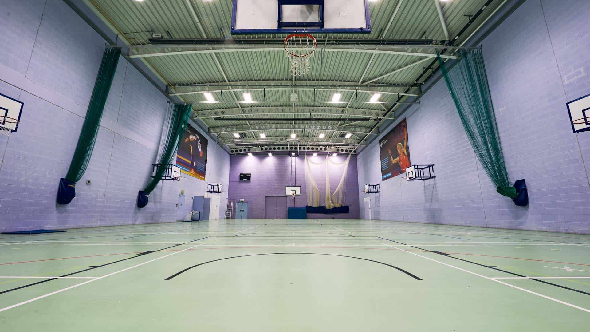 Inside the sports hall, with a various courts on the floor and basketball hoops ready for use