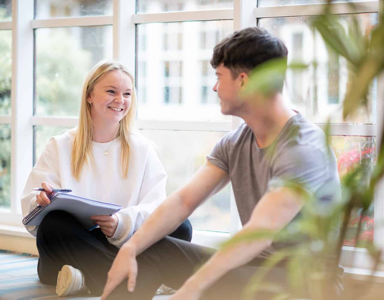 two students smiling and doing work