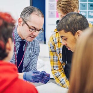 Biology teacher and a pupil inspecting something in the teacher's hands