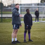 Physical Education students coaching a secdonary school pupil on a football pitch