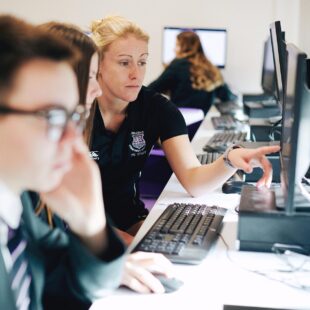 teacher helping pupils with IT work