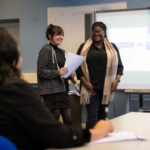 two business students presenting in front of a class