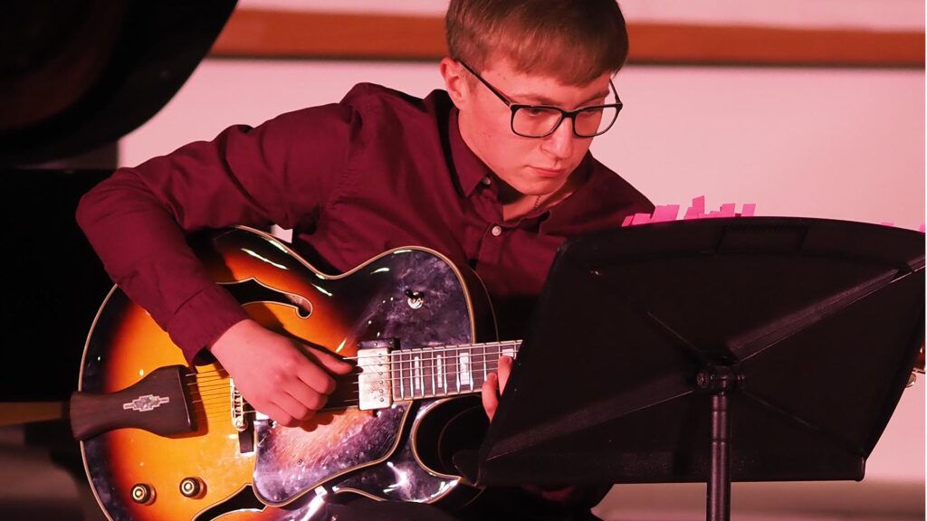 Student playing guitar on stage