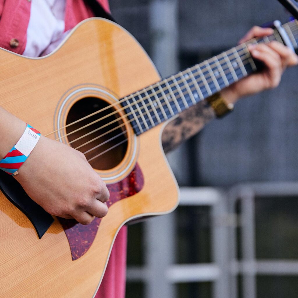 Student performing on stage with guitar