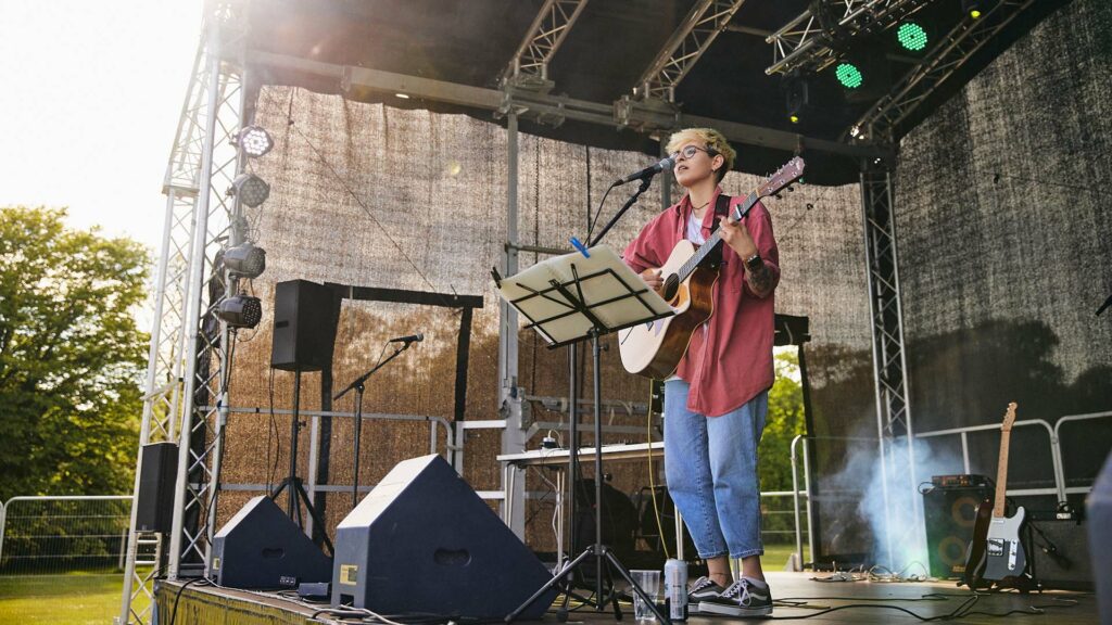 Student performing on stage with guitar