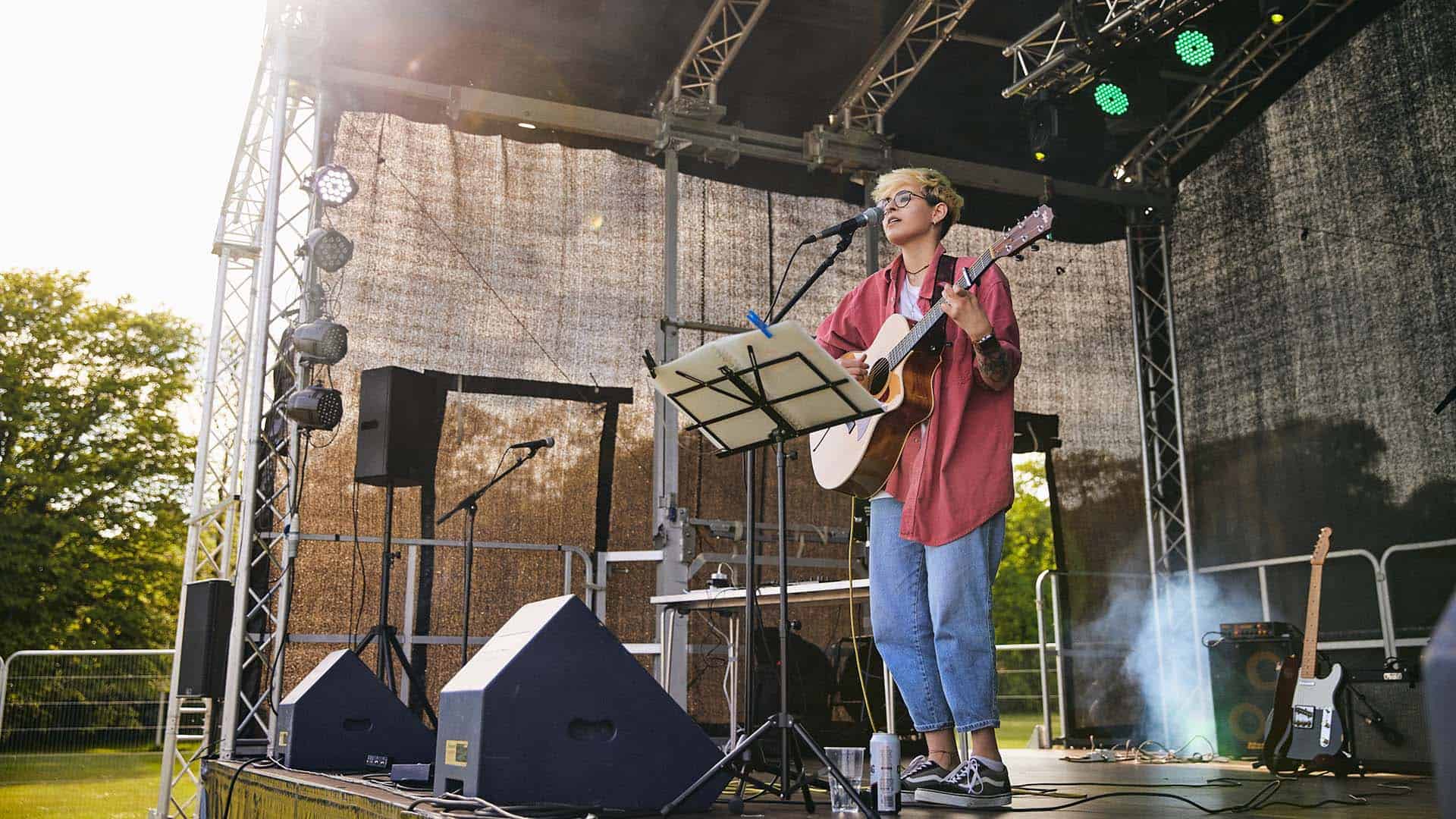 Student performing on stage with guitar