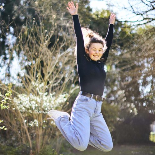 Jumping smiling student outside