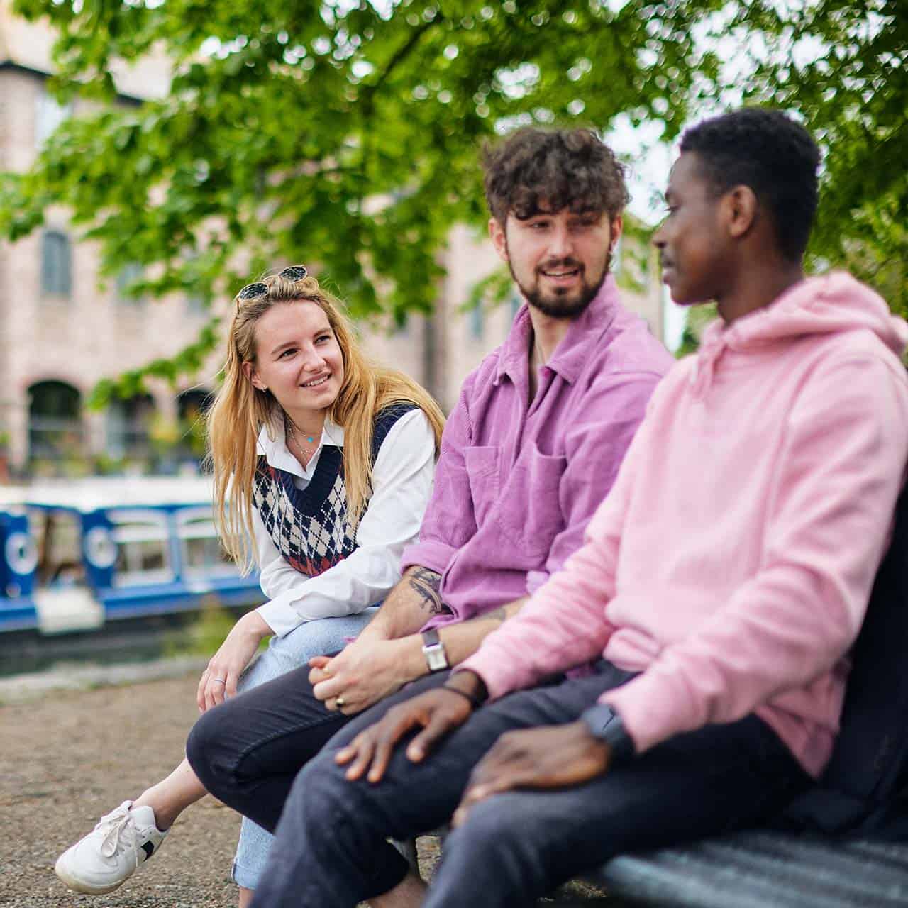 students sitting on a bench by chichester canal