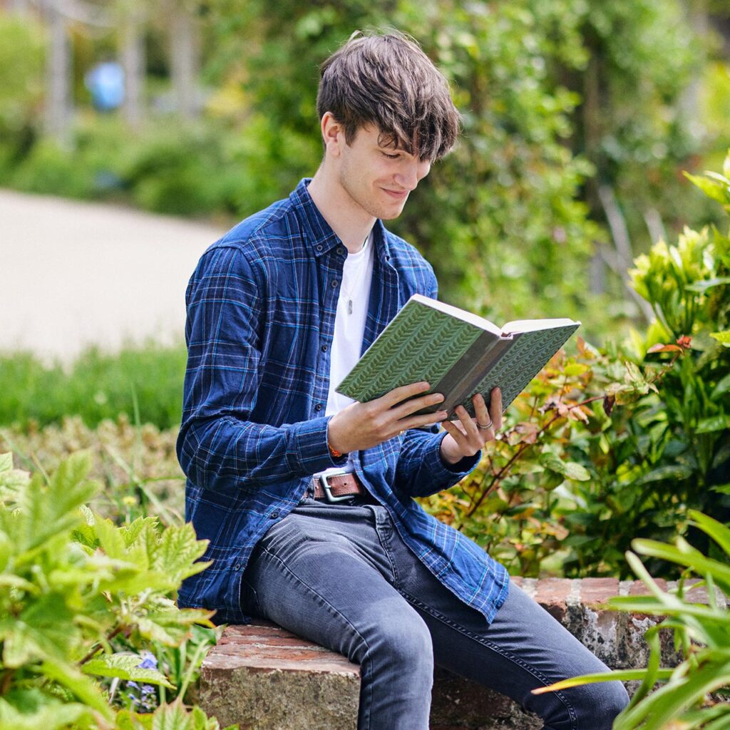 Student sat outside reading a book