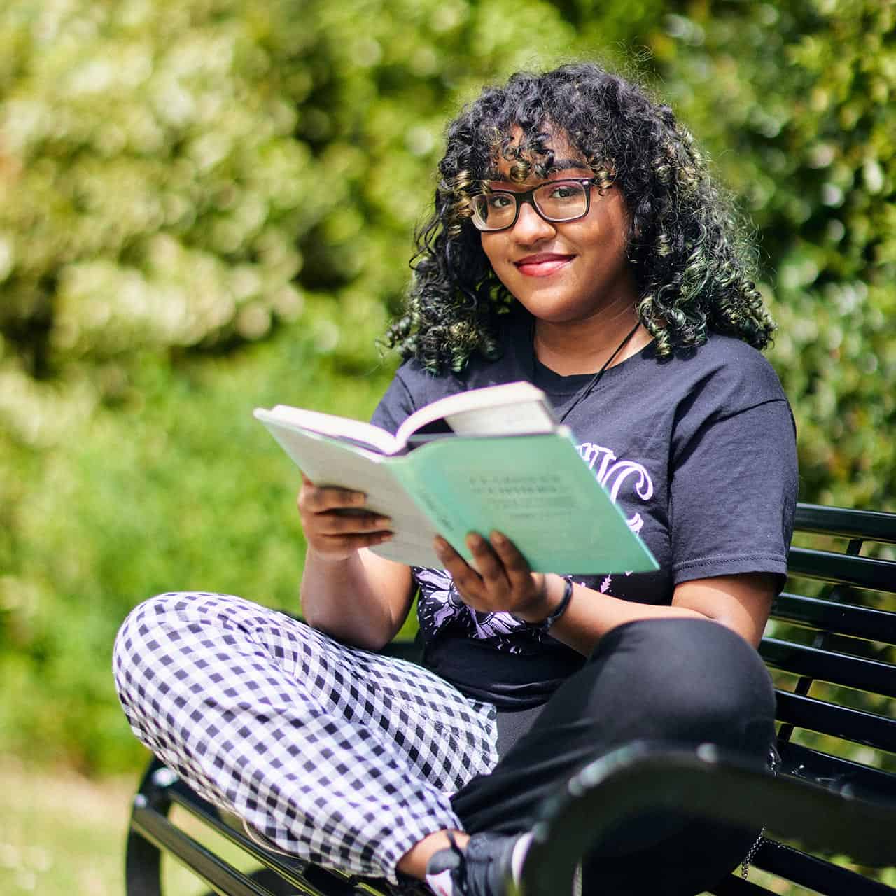 Student reading a book on a bench