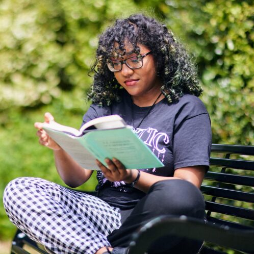 Student reading a book on a bench