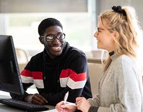 two students in the library working at computer