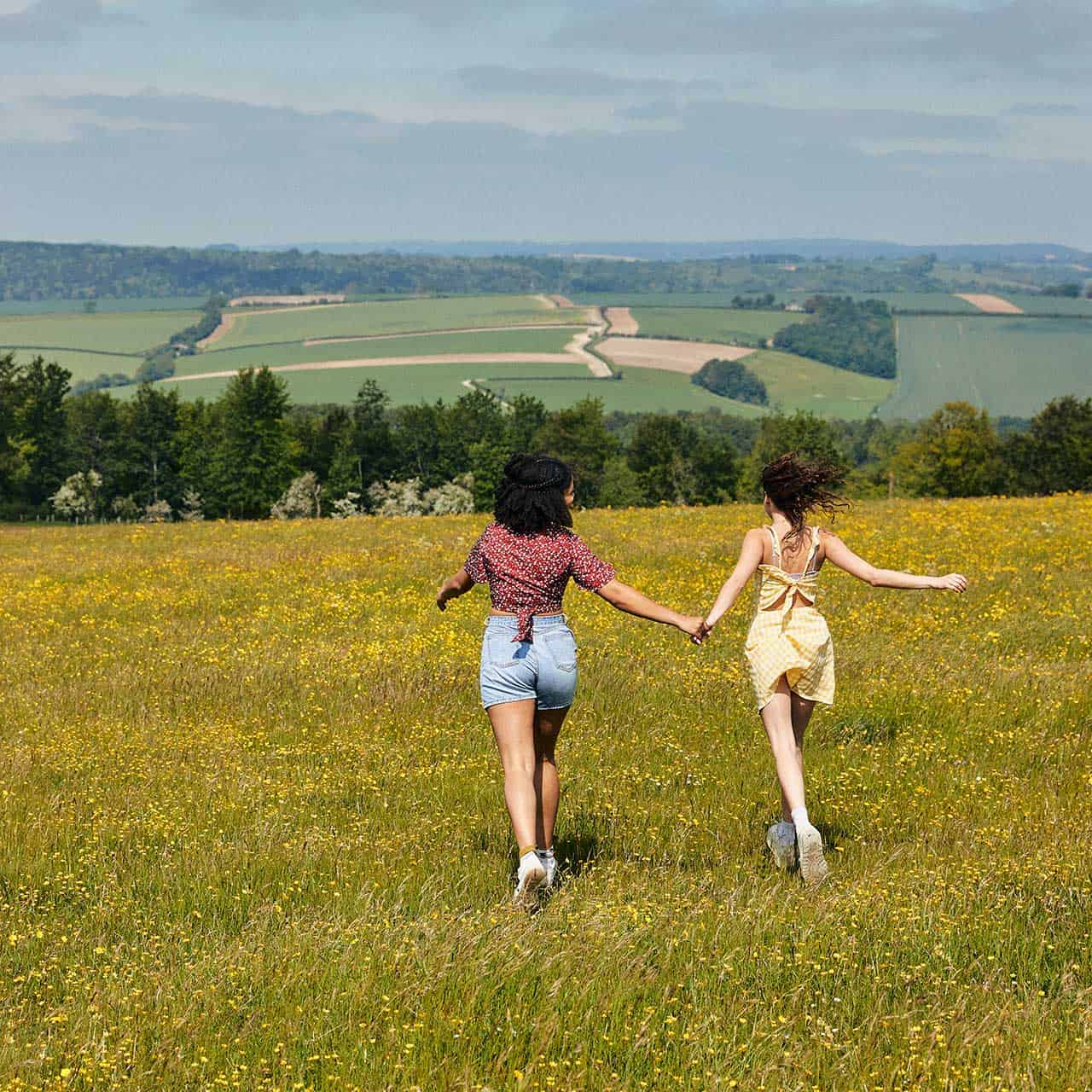 two students walking on field holding hands