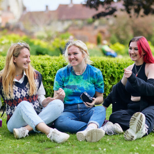 three students sitting in a park