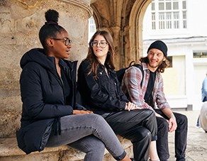 three students sitting on a bench outside