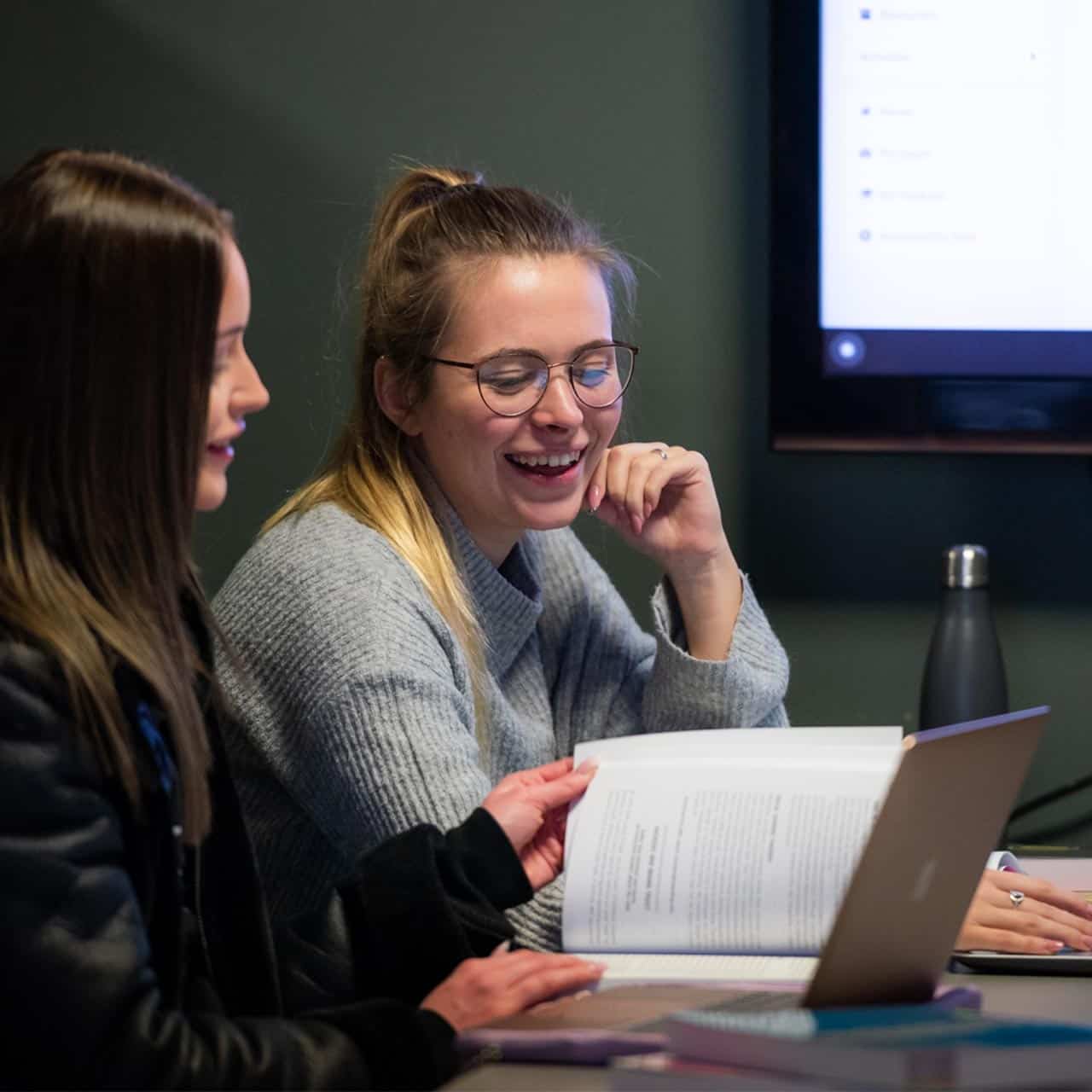 Students smiling looking at a book