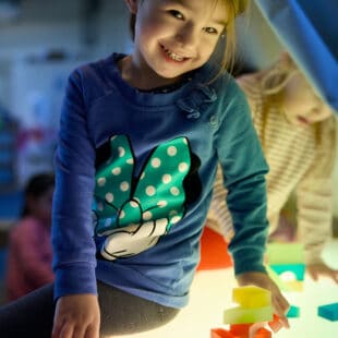 young child smiling in a pretend tent