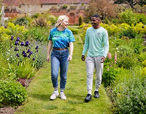 two students walking outside surrounded by flowers