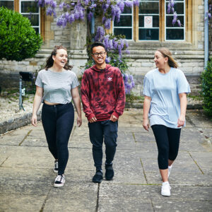 3 smiling students outsides Cloisters