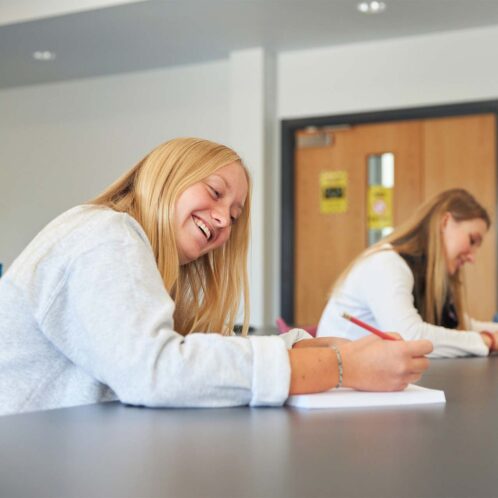 Smiling student writing on paper