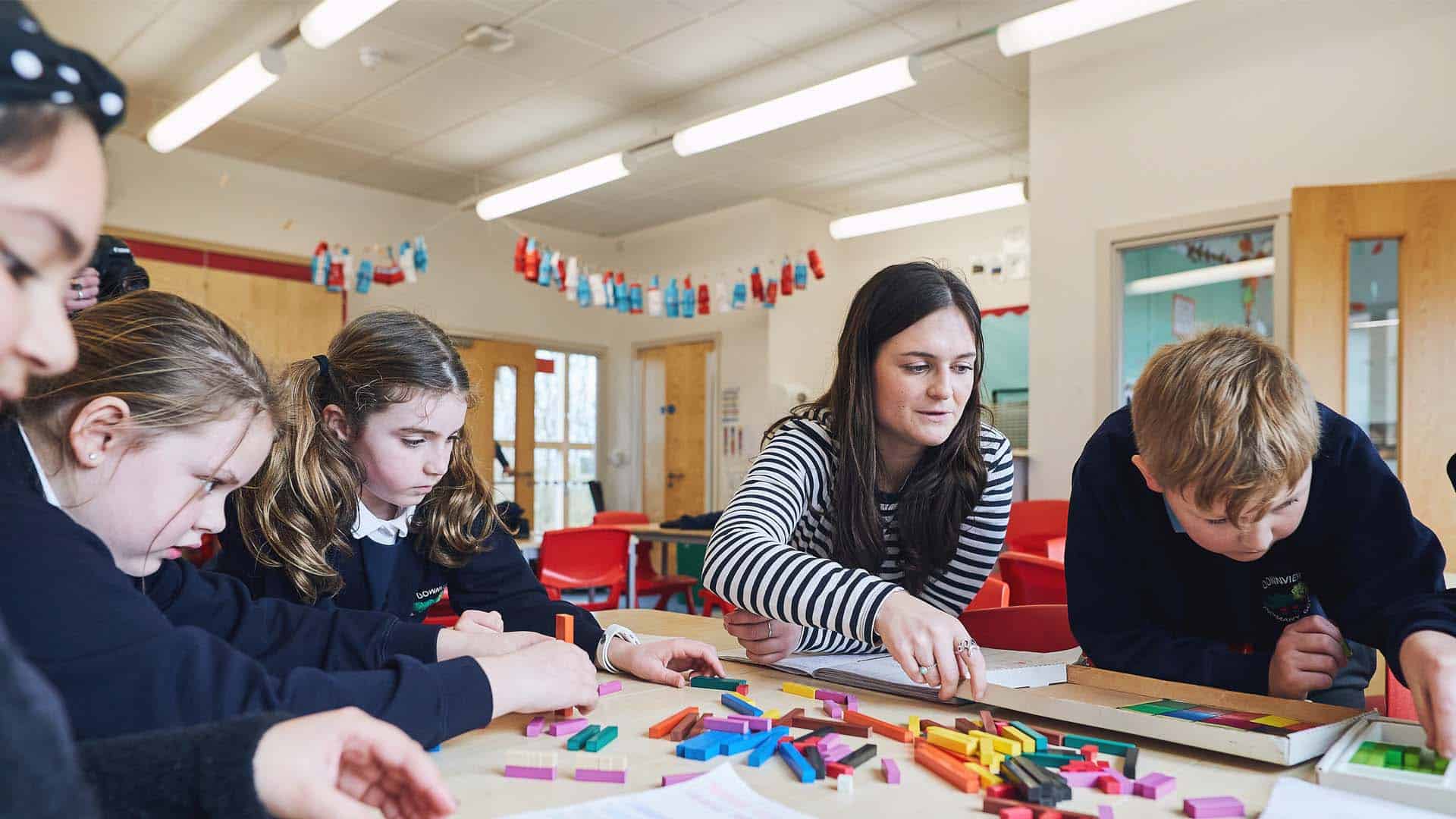 Teaching student helping pupils with their work on placement