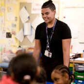 Qualify as a teacher Teaching student smiling as they lead a primary school class
