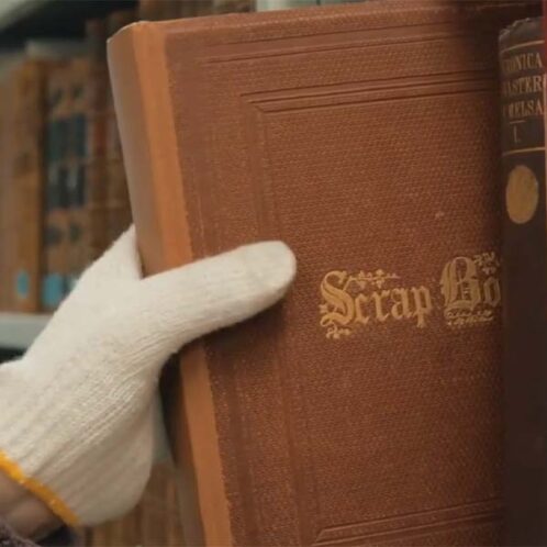 A hand removing an old book from the shelf