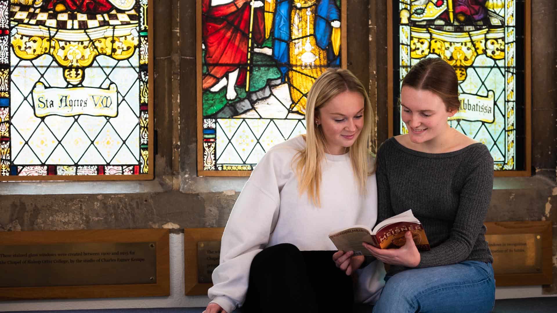 two students reading a book together