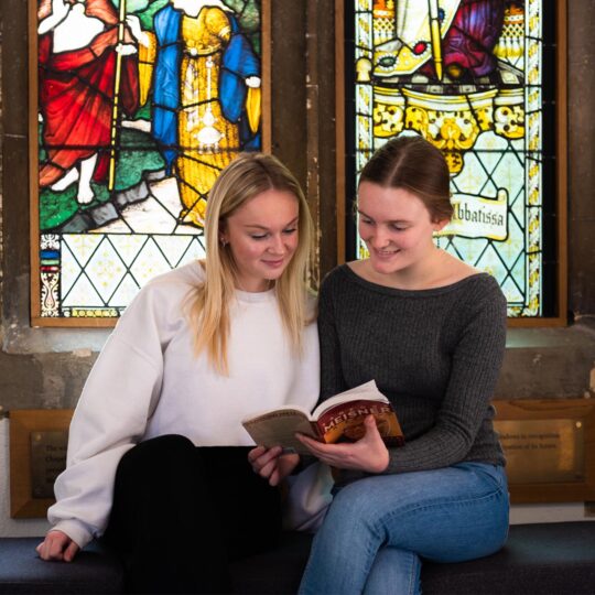 Students reading in front of stained glass window