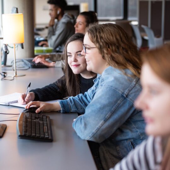 Students smiling and researching on Library computers