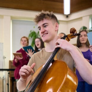 Student playing a cello in a classroom