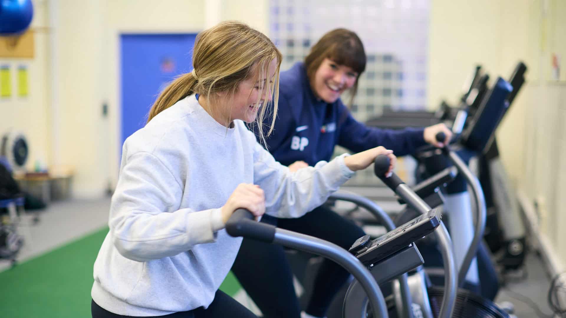 Two students on exercise bikes in the gym