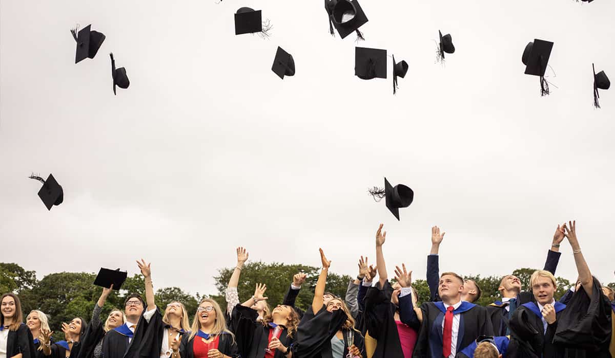 students throwing graduation hats in the air