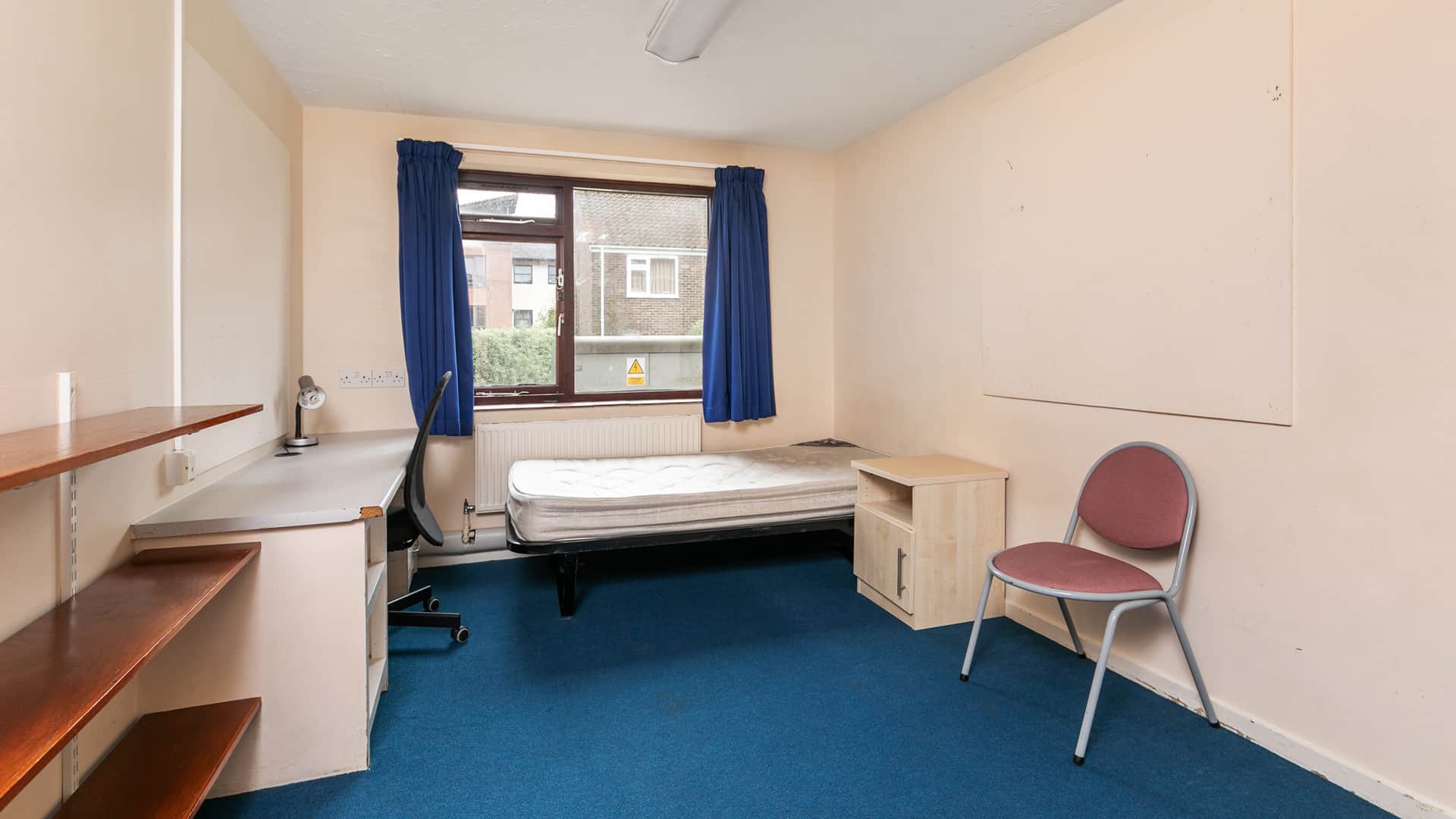 bedroom with a single bed, a desk with a swivel chair, a small wooden cabinet