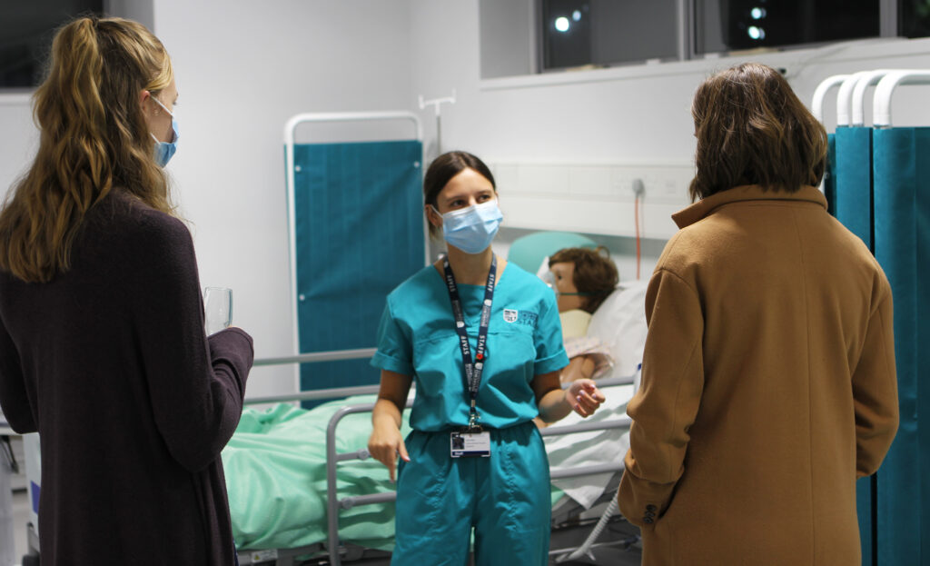 Nursing student in scrubs talking to visitors