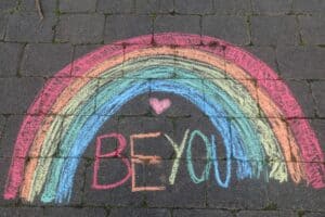 Chalk rainbow drawing that says 'Be You' on pavement