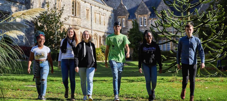 Six students walking towards camera outside of Cloisters