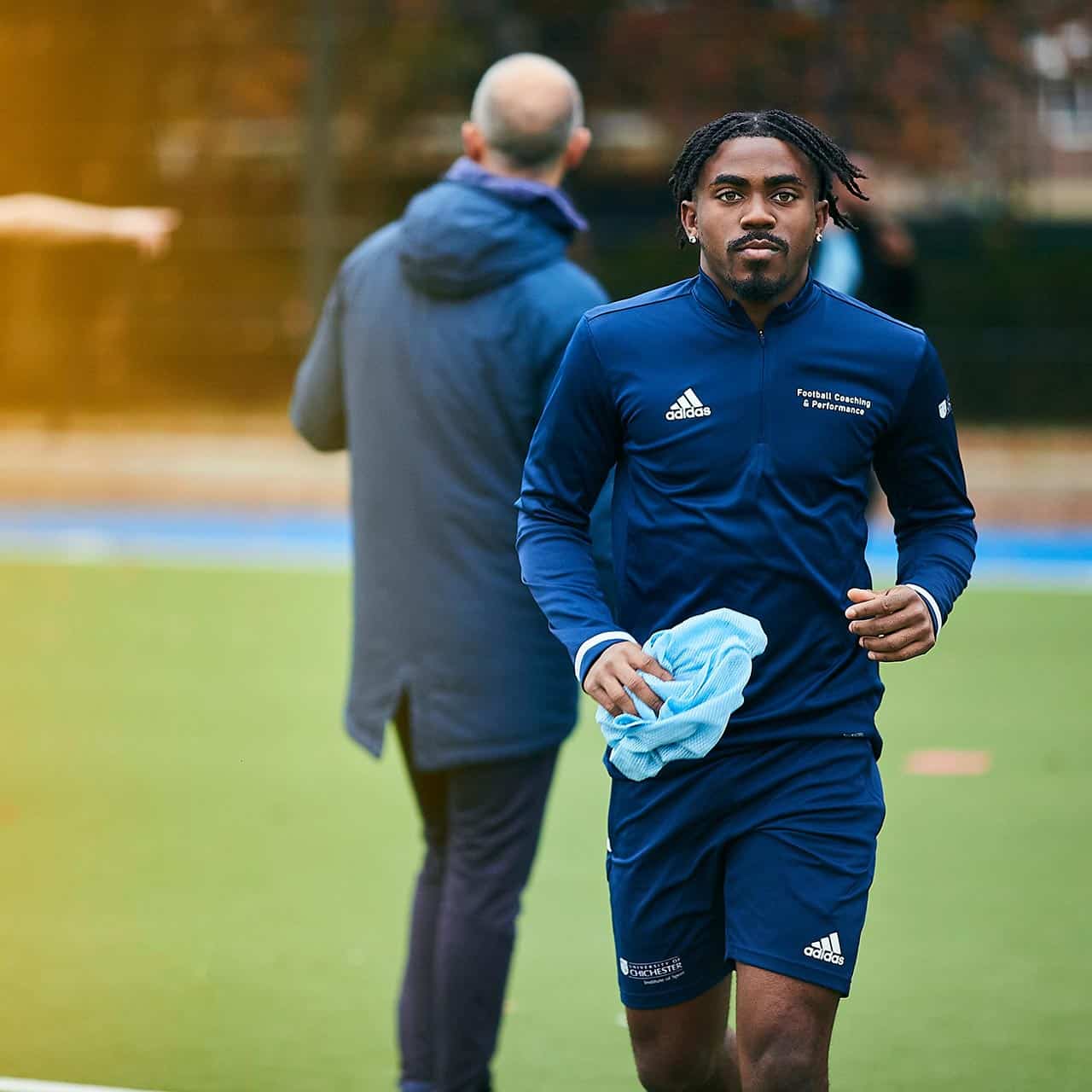 male student walking on football pitch