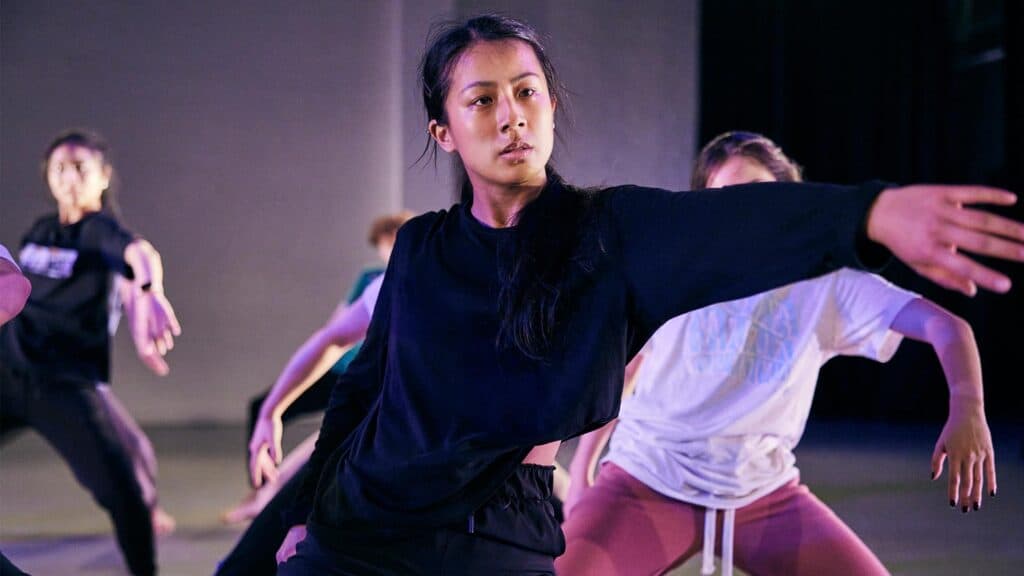 Dance students rehearsing a piece with stage lighting