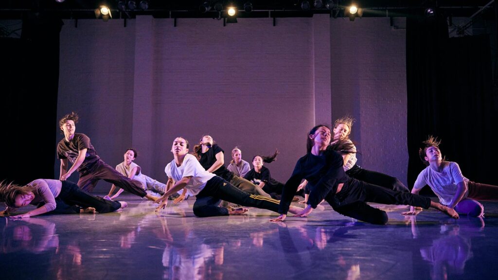 Dance students rehearsing a piece with stage lighting