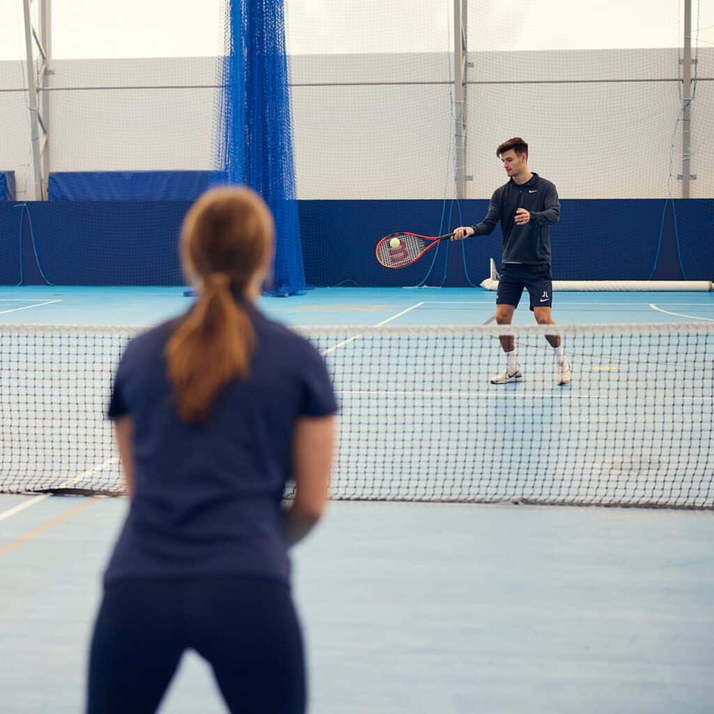 Male and Female student playing tennis