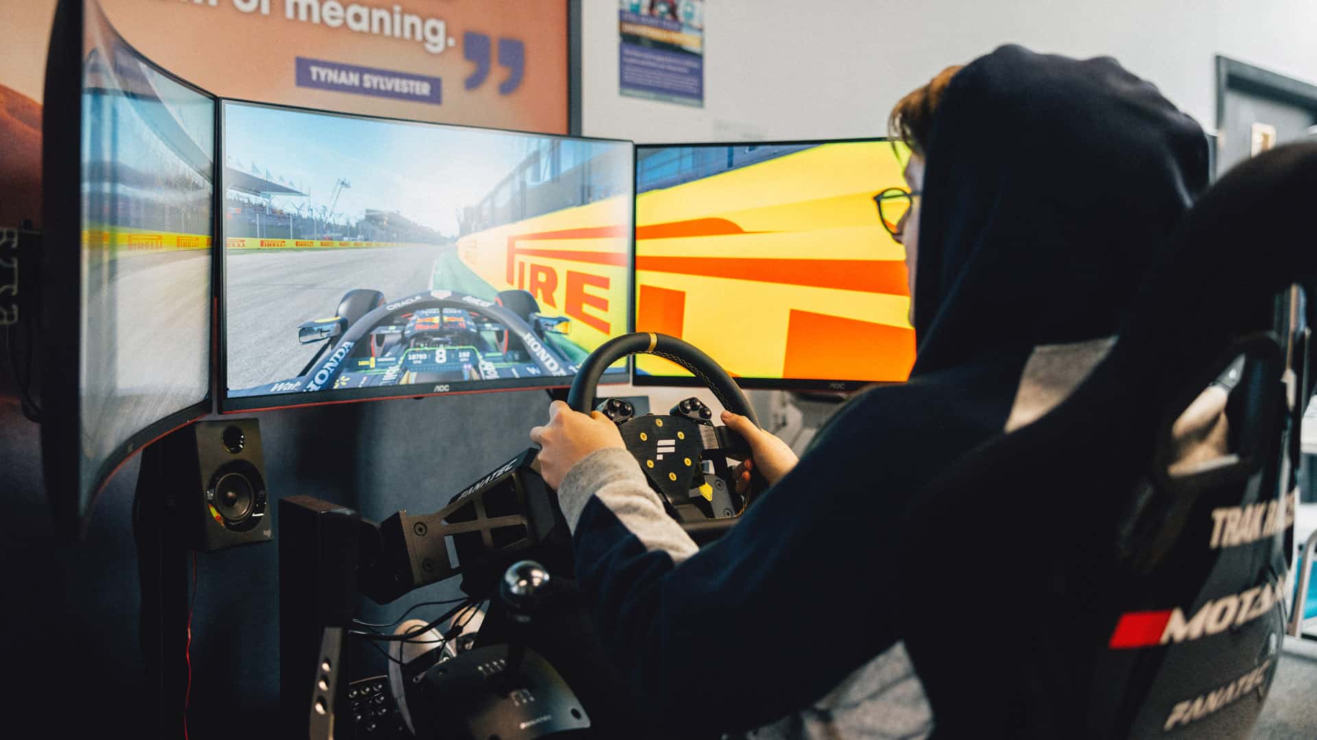 Esports student playing racing game with a gaming setup including a steering wheel