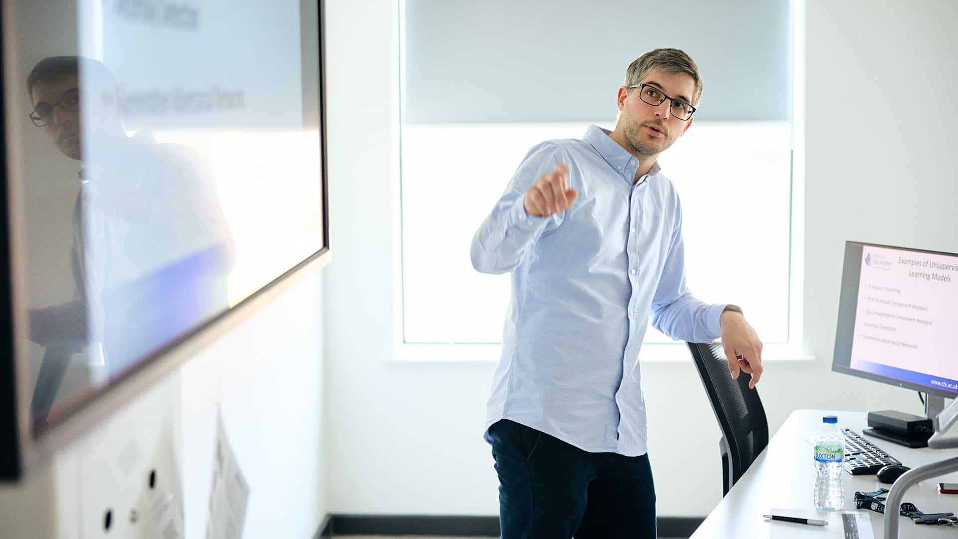 Lecturer pointing to a screen in a class