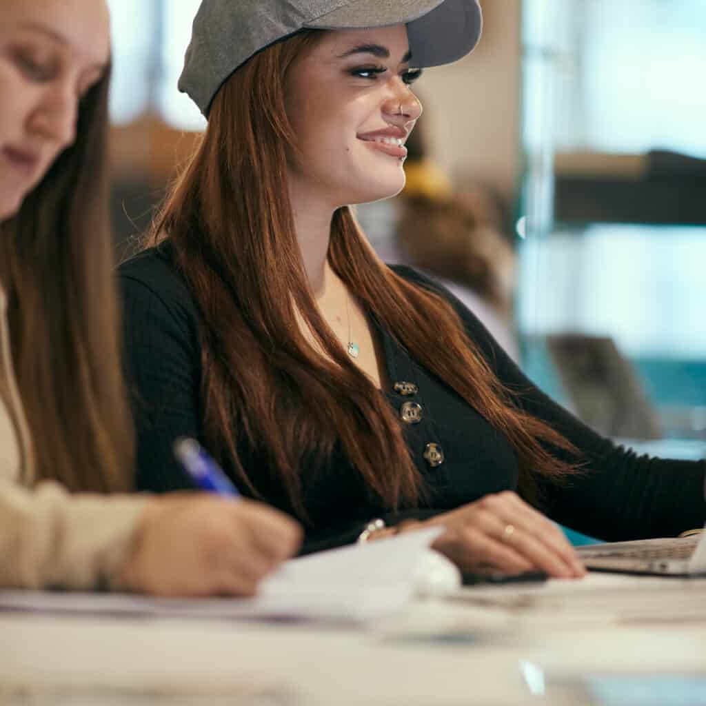 student smiling with friends at computer